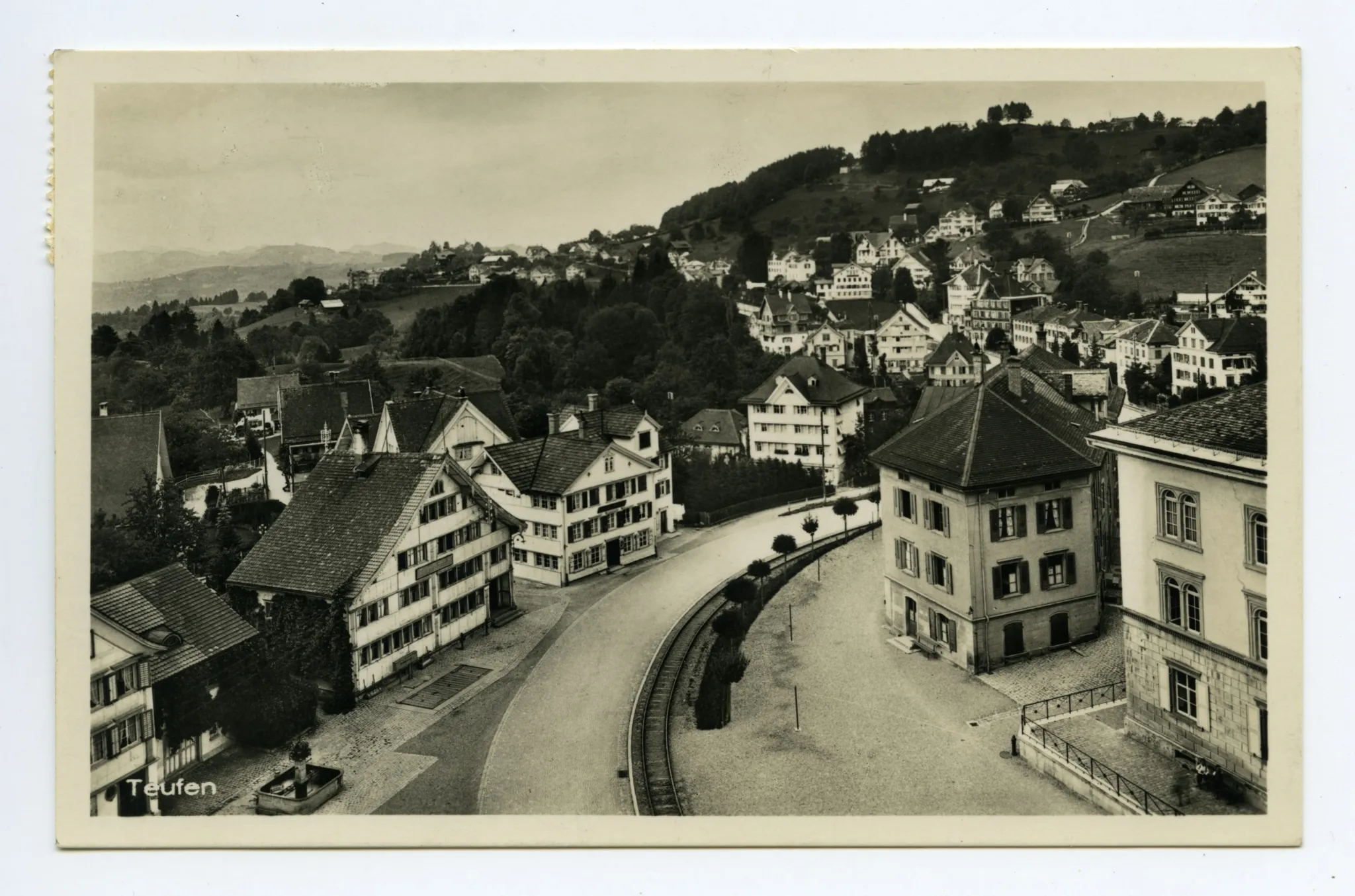 Dorfschulhaus (z.T.), Alter Bahnhof, Gasthaus „Bahnhof“ mit Brückenwaage, alter Dorfbrunnen, Konsum-Verein. Blick Richtung Stofel / Eggli, Frohe Aussicht (vgl. Hc.20.19, Kartenauflage b statt g)