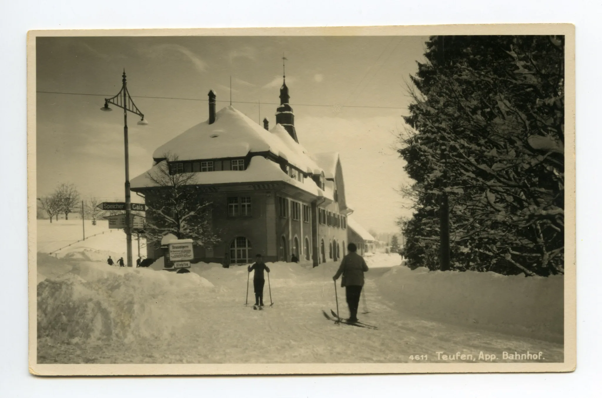 mit Tafel „Strassensperre – Erdrutsch am Stoss“, mit zwei Skiläufern auf der schneebedeckten Strasse