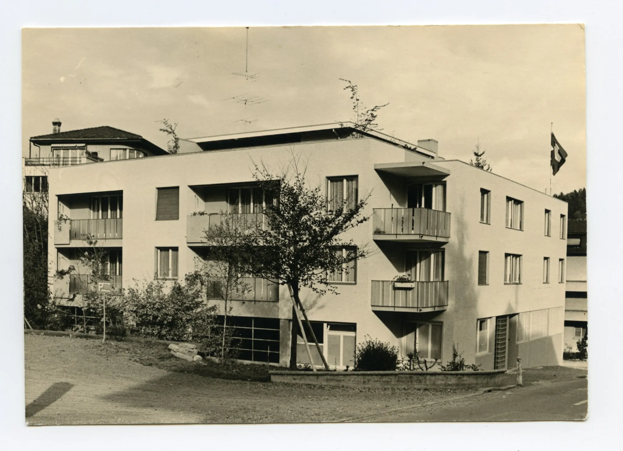 Karte 1: Firmenkomplex mit Eingangsbereich und parkenden Autos; Karte 2: Rückansicht des Firmengebäudes (Mietwohnungen mit Balkon)