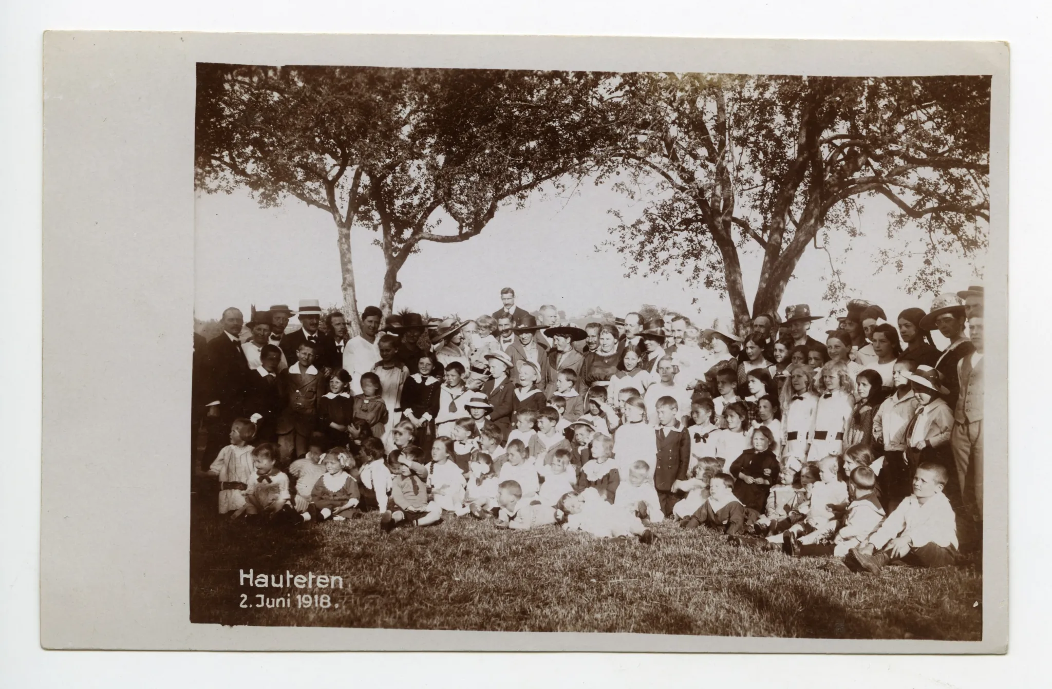 Gruppenbild auf Wiese, alle Personen sind festlich gekleidet, Kinderfest?