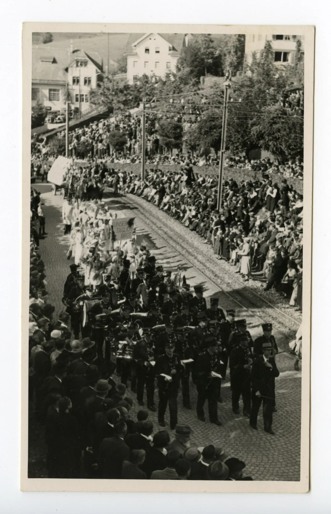mehrere Gruppen, Musikanten, Bäcker, Mehlfuhrwerk, auf der Hauptstrasse, im Hintergrund alte Dorfturnhalle
