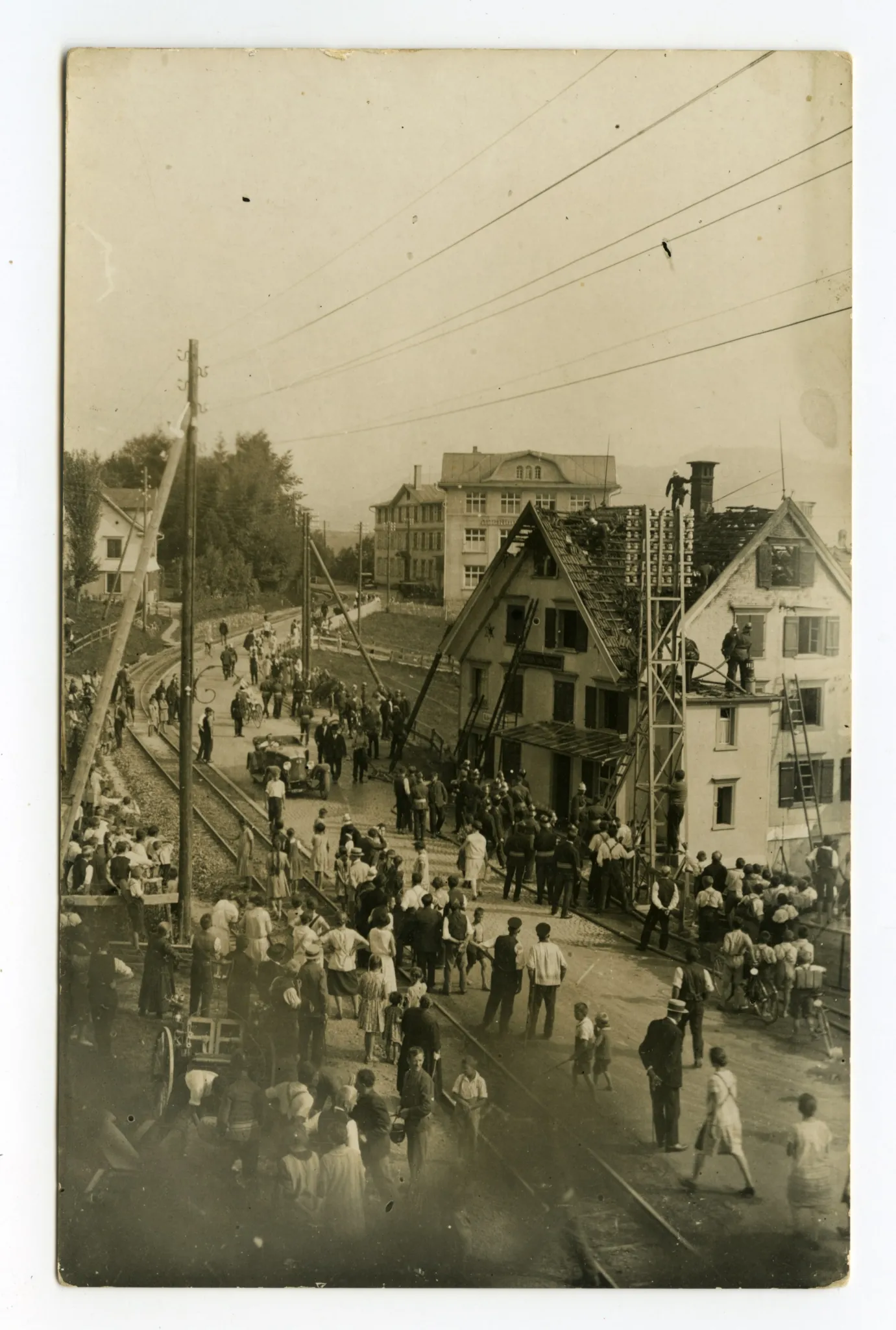 (11. Sept. 1929), Ansicht des Hauses mit Feuerwehrmännern beim Löschen, viele Schaulustige, Bahngleis sichtbar, Blick Richtung Druckerei-Kunz