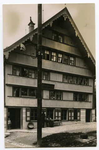 Ansicht mit Bewohner vor dem Haus und aus dem Fenster schauend