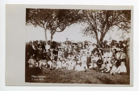 Gruppenbild auf Wiese, alle Personen sind festlich gekleidet, Kinderfest?