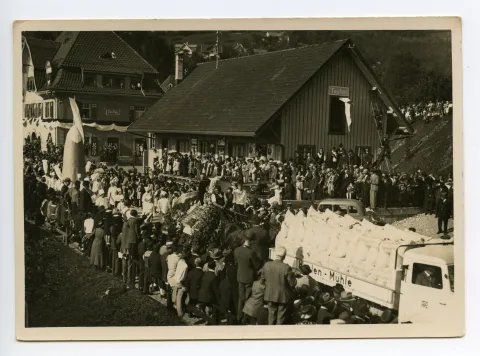Lastwagen beladen mit Mehlsäcken der Haslen-Mühle?, gefolgt von Fuhrwerk der Obst- und Gemüsebauern, gefolgt von Konditoren auf der Strasse, Ebni, Güterschuppen und Bahnhof sichtbar